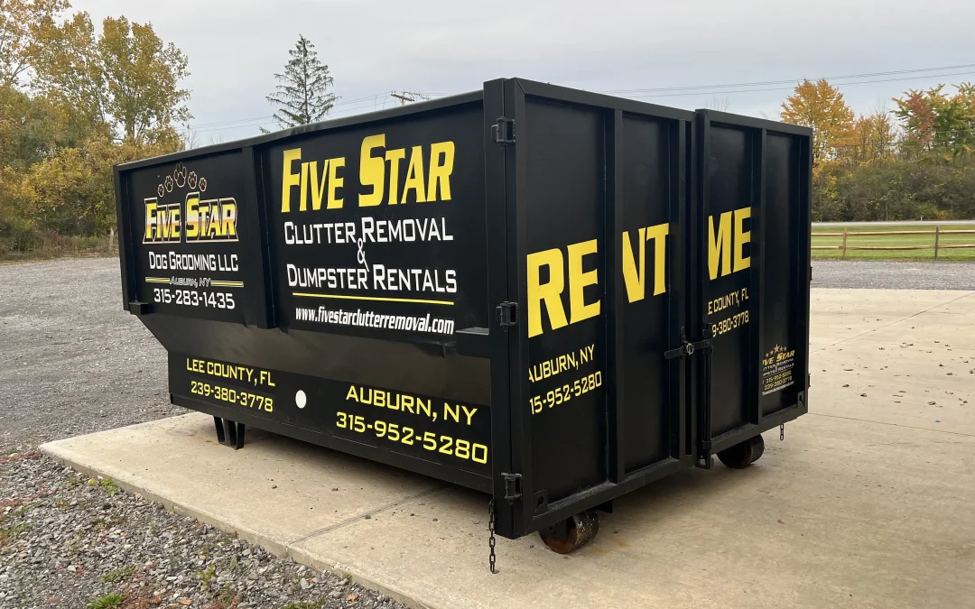 A black rental dumpster with "five star clutter removal" branding parked on a gravelly surface.