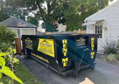 A black dumpster parked in front of a house.