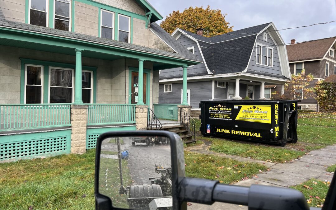 A house with a green trim and a black and yellow container.